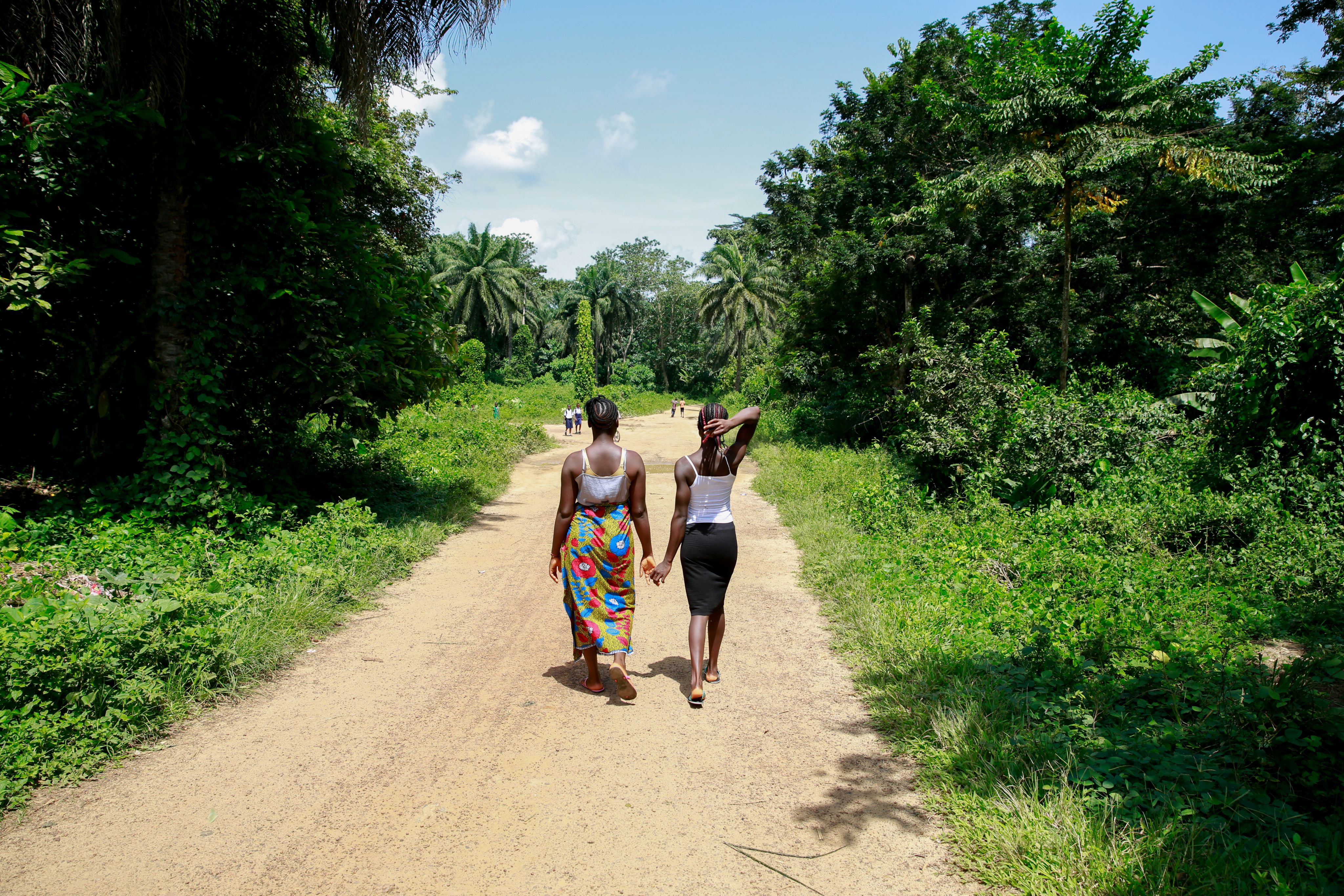 Cousins Kpemeh*, 18 and Kuji*, 19 walkign holding hands, Sierra Leone.