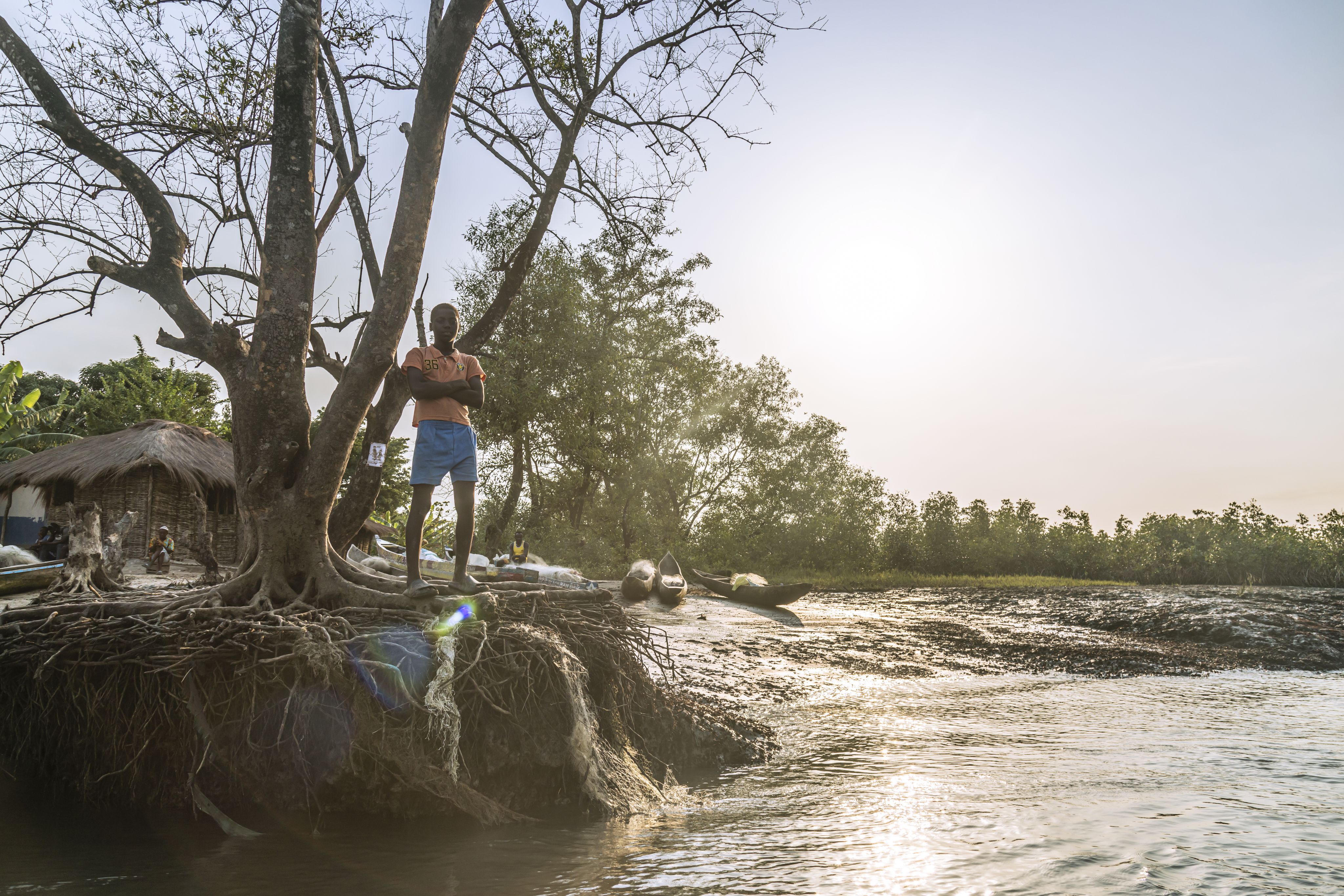 Abdulaye*, 11, stands on top of an eroding tree at the front of the Djelah village, Sierra Leone.