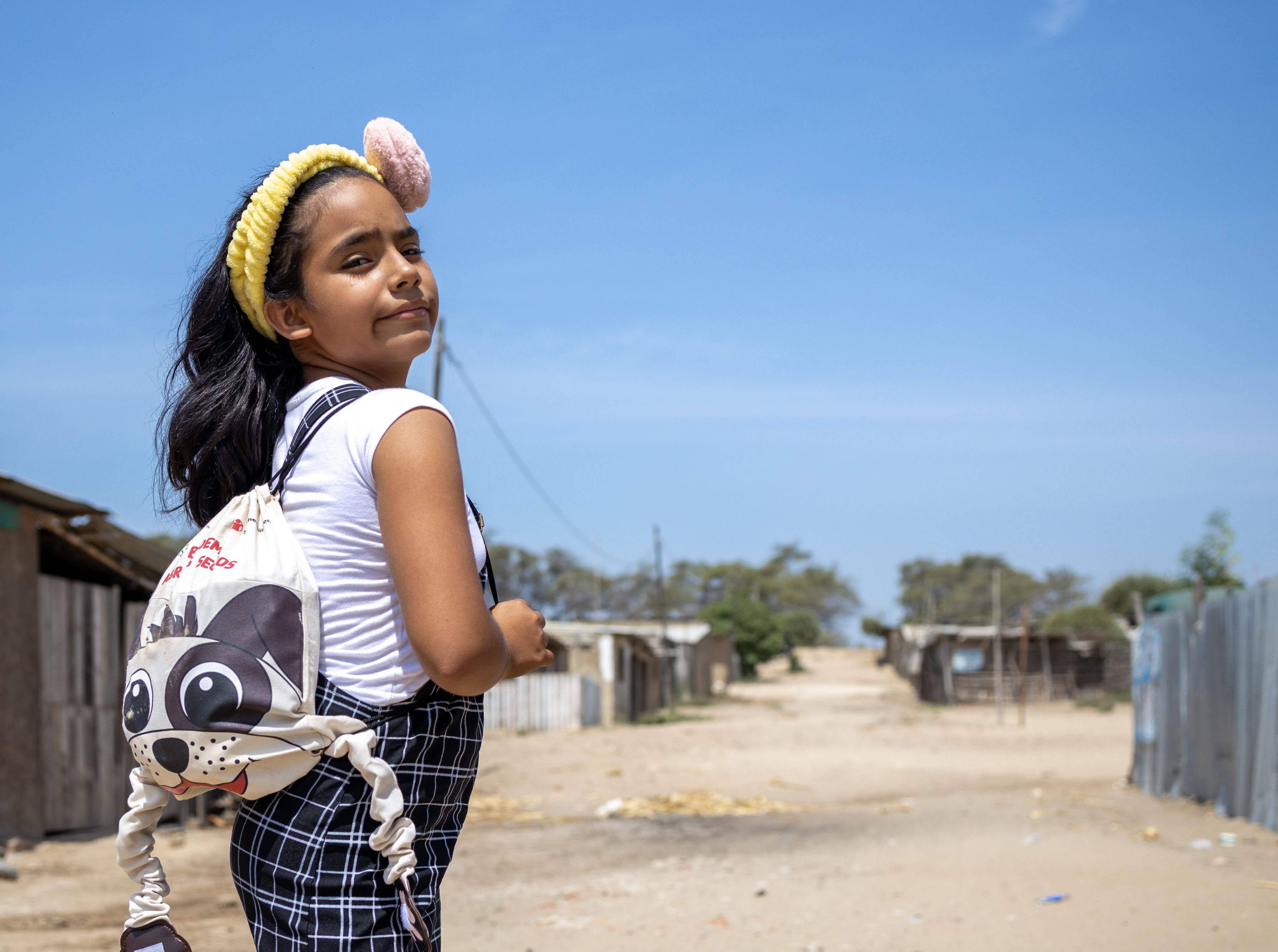 Yaira, 11, wearing a yellow headband and 'Panchito', the huggable backpack, Peru