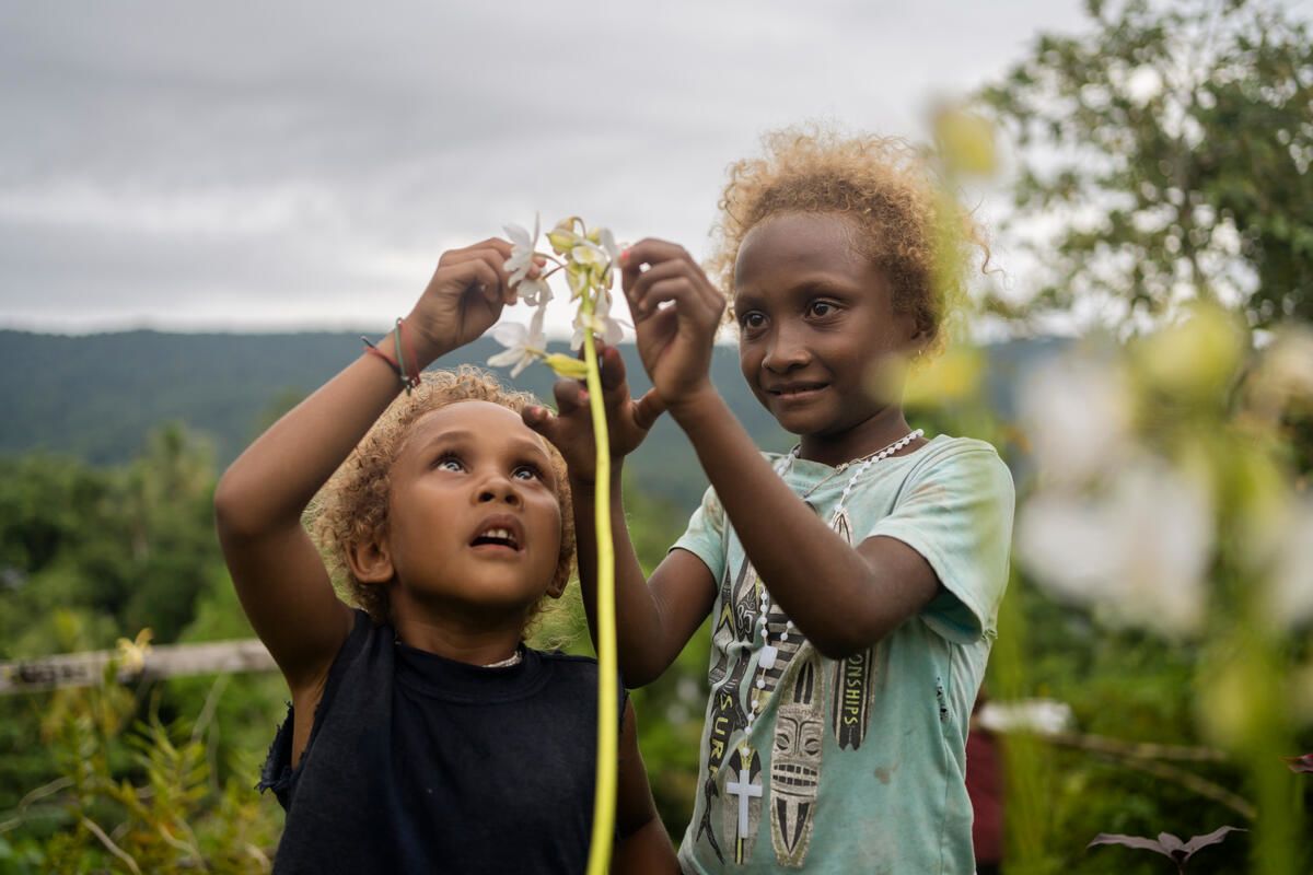 Josephine, 7, and Lucy, 4, pick flowers from a garden outside their home in Malaita Province, the Solomon Islands.