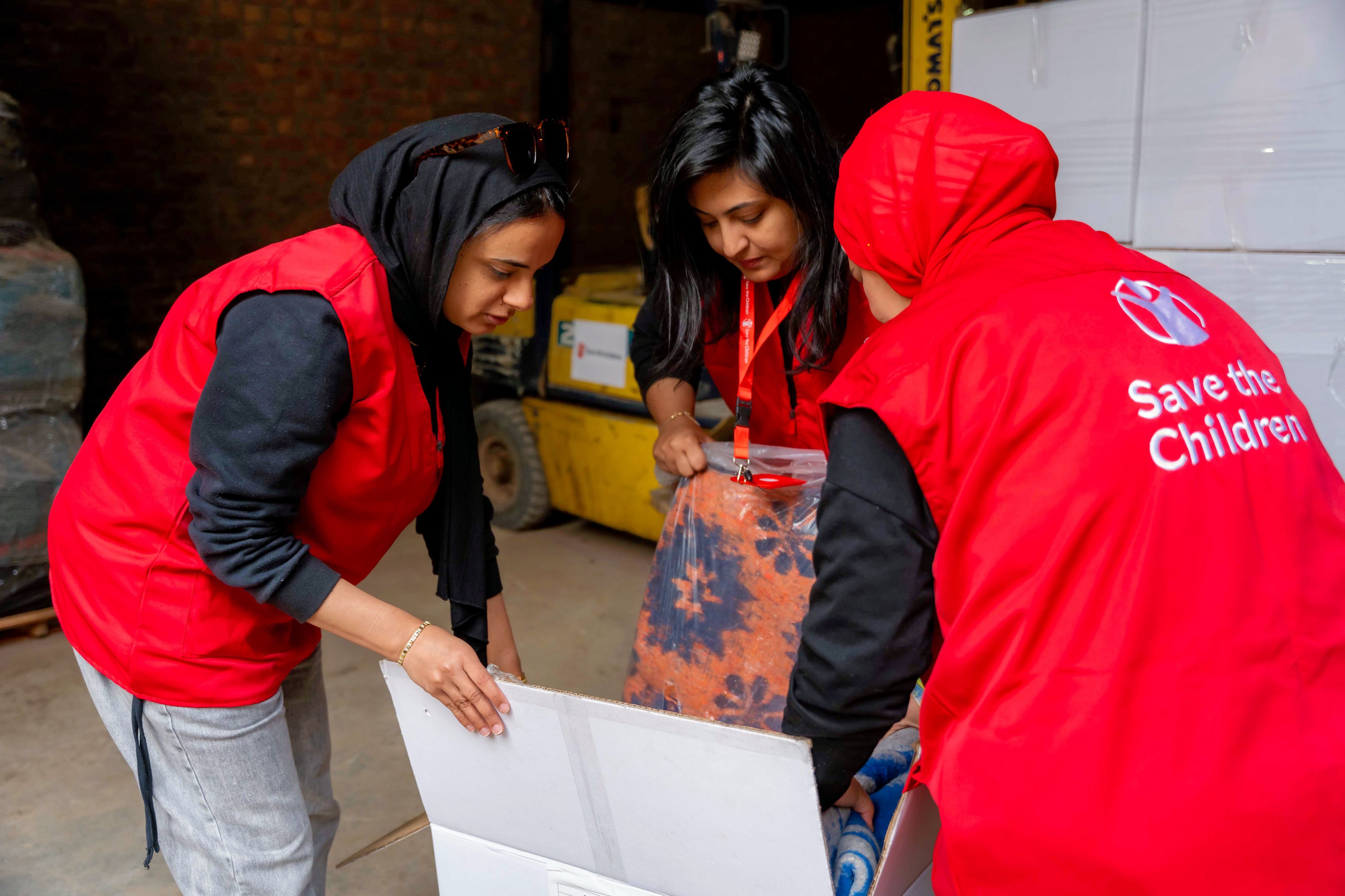 Omar* and sons Ali* and Ahmed* inspecting the food parcel provided by Save the Children