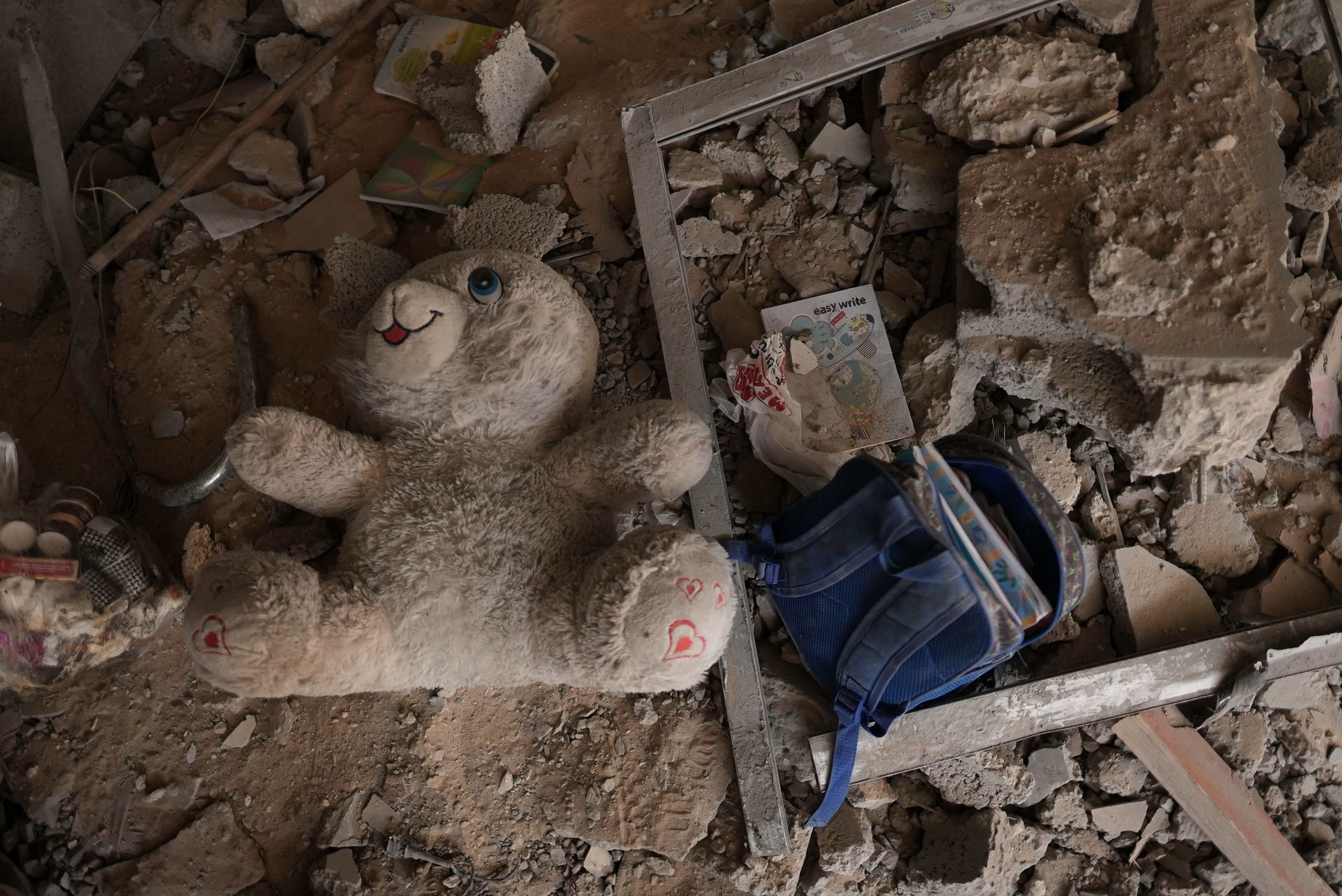 A child's school backpack and a doll among a rubble in Gaza